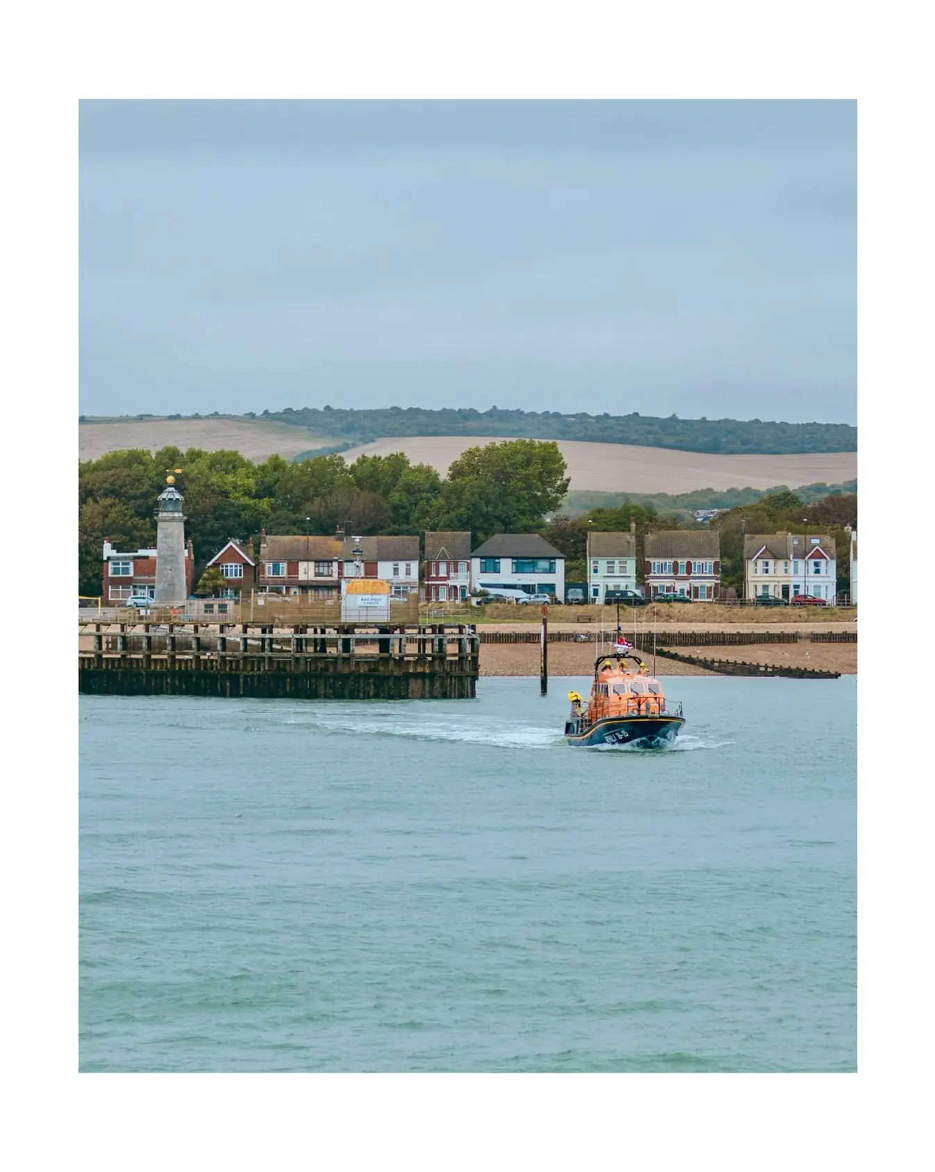 RNLI lifeboat heading out past the lighthouse at Shoreham harbour